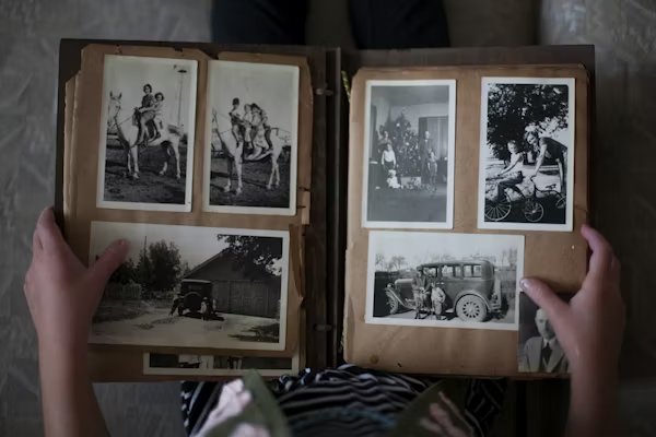 An old family photo album being held open — photographs from another era